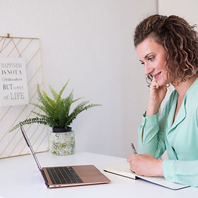 Anja bei einer Coaching Session. Lächelt und notiert etwas.